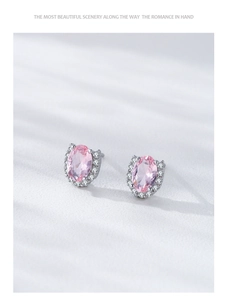 Macro shot of oval pink gemstone stud earrings with sparkling halo and silver base