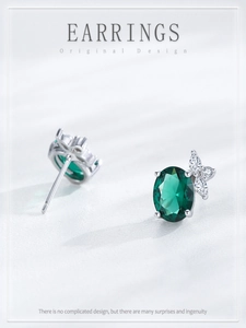Détail de boucles d'oreilles en argent avec émeraude ovale et accent papillon