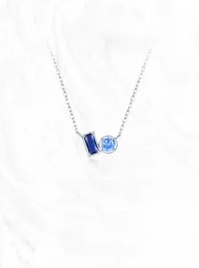 Detail of S925 silver necklace featuring tiered blue zircon crystals on marble background