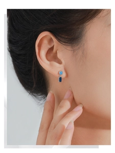 Close-up of S925 silver earrings with rectangle blue stones on model's ear