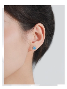 Close-up of S925 silver square stud earrings with sky blue gemstone on woman's ear