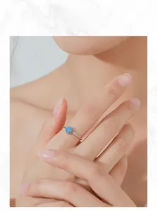 Detail of S925 silver flower ring with blue crystal on hand with soft skin tone