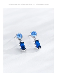 Close-up of S925 silver earrings featuring blue round and emerald-cut cubic zirconia