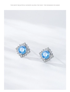 Macro shot of silver sunflower earrings featuring light blue stones and zircon clusters