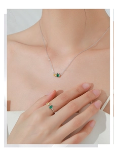 Detailed view of teardrop emerald and yellow gemstone ring on a female finger