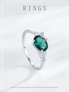 Macro view of sterling silver ring with oval emerald zircon and marquise side stones