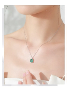 Detailed view of an S925 silver necklace with emerald-green rectangular pendant on a neck
