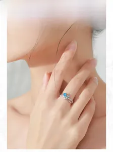 Detail of silver bow ring featuring sea blue teardrop zircons on a model's hand