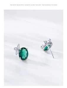 Vue macro de boucles d'oreilles ovales en argent et émeraude avec motif feuille