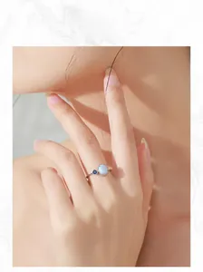 Detailed view of the S925 silver opal ring with sapphire side stone on a model finger