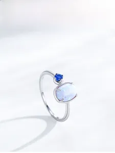 Detailed view of S925 silver ring featuring oval opal and round blue sapphire accent