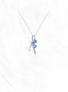Detail of S925 silver bow pendant with blue teardrop gemstones and micro-pave zircons