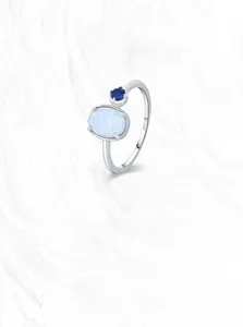 Macro detail of S925 silver ring featuring oval white opal and round blue sapphire
