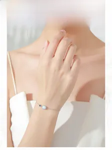Close-up of S925 silver chain bracelet featuring blue gem and white opal on female wrist