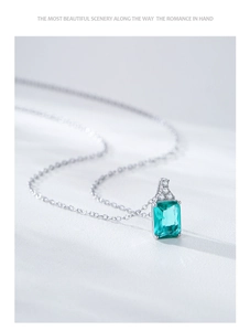 Macro detail of the rectangular emerald green gemstone pendant on a fine silver chain