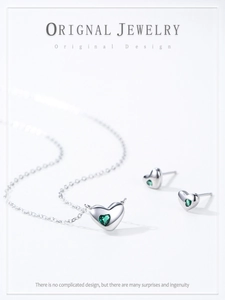 Gros plan d'une parure en argent S925 avec cœurs et zircons verts sur fond blanc