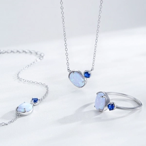 Elegant S925 silver jewelry set with oval opal stone and blue gem accents on a white surface