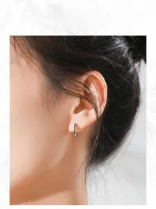 Model wearing silver geometric hoop earrings with black zircon stones in a side view