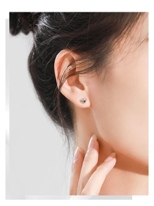 Close-up of heart-shaped S925 silver stud earring with a central green gemstone detail