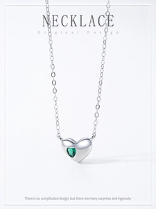 Macro detail of S925 sterling silver heart necklace with a sparkling green gemstone