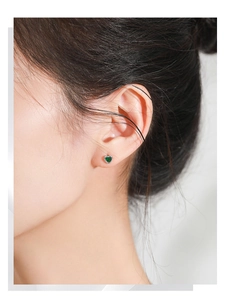 Close-up of elegant S925 silver heart stud earrings with green emerald zircon on ear