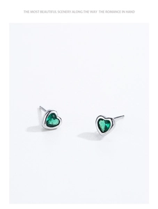 Macro detail of heart-shaped S925 sterling silver studs with emerald green zircon stones