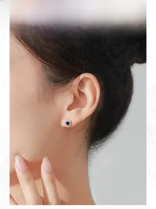 Close-up of model wearing a vintage S925 silver heart earring with deep blue stone