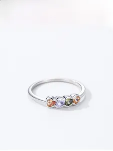Detail of silver ring featuring four colorful heart-shaped gemstones on white background