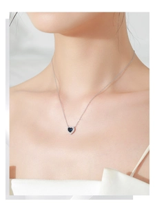 Close-up of S925 silver heart necklace with deep blue gemstone on a female model