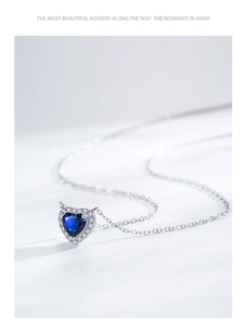 Detail of the heart-shaped blue sapphire pendant with sparkling diamond halo on silver chain