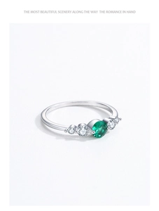 Macro shot of S925 silver ring featuring a round green emerald and white side diamonds