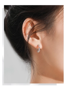 Detailed close-up of a silver hoop earring featuring colorful inlaid zircon stones on model