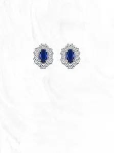 Macro detail of 925 silver flower stud earrings with oval sapphire and halo zircon