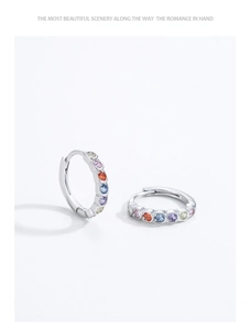 Macro detail of silver hoop earrings with a colorful rainbow cubic zirconia inlay