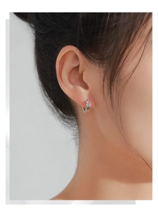 Détail de zircons colorés en forme de cœur sur des créoles en argent S925 à l'oreille