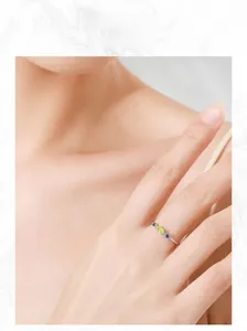 Détail d'une bague en argent 925 avec des pierres précieuses vertes et bleues au doigt