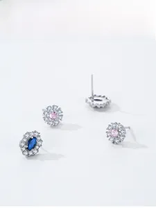 Close-up of snowflake stud earrings with sparkling blue and pink crystals on silver base