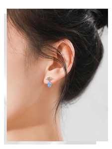 Macro detail of 925 silver earring with Saturn ring design and blue opal-like stone