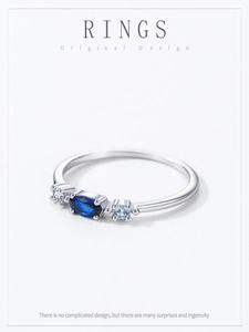 Macro shot of silver ring featuring oval blue sapphire center and side diamond accents