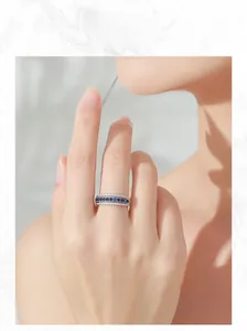 Close-up of model wearing a 925 sterling silver ring with blue sapphire and pavé diamonds