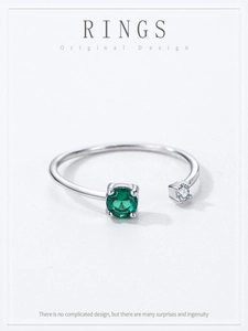Détail macro d'une bague ajustable en argent avec zircon rond vert et pierre blanche