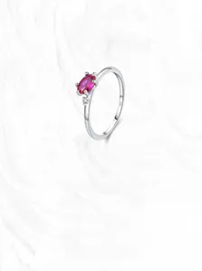 Macro shot of 925 silver ring featuring an oval pink gemstone on marble background
