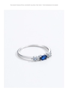 Macro detail of silver ring featuring an oval blue sapphire and four-prong setting