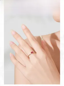Macro detail of a 925 silver ring with oval ruby and sparkling side stones on a finger