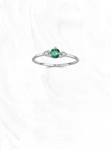 Macro detail of S925 sterling silver ring featuring a round green emerald and side stones