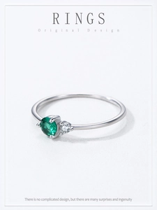 Detail of 925 sterling silver ring with small emerald zircon and clear side stone
