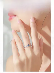 Macro detail of an elegant sapphire silver ring with side diamond accents on model's finger
