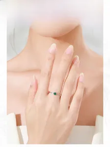 Close-up of minimalist silver ring with round green emerald zircon worn by a model