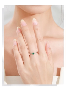 Close-up of minimalist 925 silver ring with green emerald zircon on a model's finger