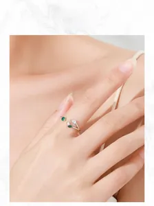 Close-up of leaf-shaped S925 silver ring with green gems worn on finger